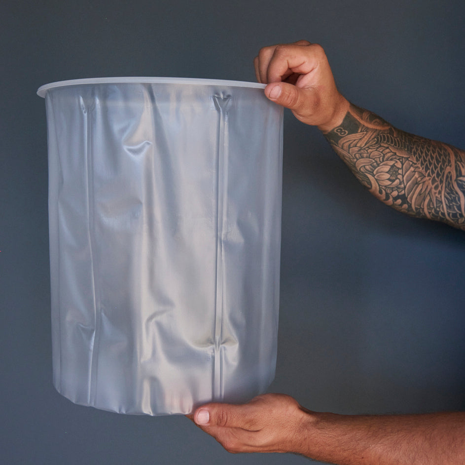 Person holding a clear plastic liner for 5 gallon buckets 
